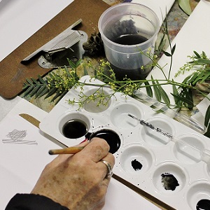 Person using ink brush to and paint pallet to pant plants.