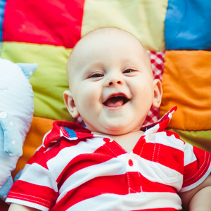 Baby smiling surrounded by colourful quilt