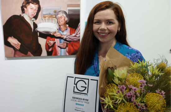 GRAP Winner Margaret Lyons smiling and standing in front of painting titled Birthday cake and Namitjira. Margaret is holding the winning award and flowers.