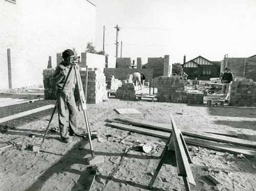 black and white picture of a construction site with a gentleman checking the group level
